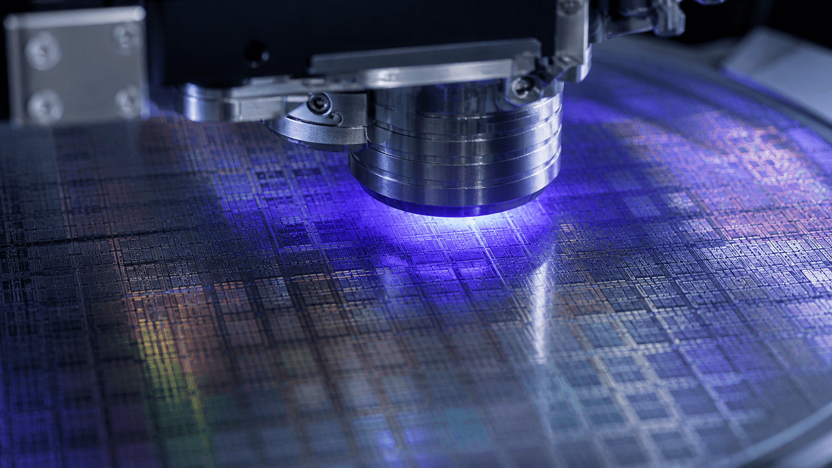 Close up of a lithography tool operating on a patterned silicon wafer illuminated by a bluepurple laser glow